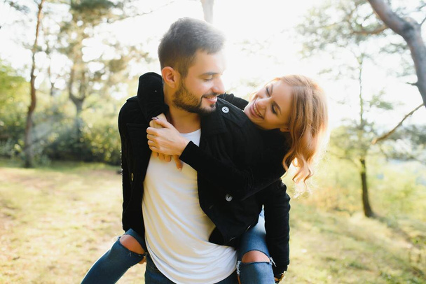 love, relationship, family and people concept - smiling couple having fun in autumn park - 写真・画像