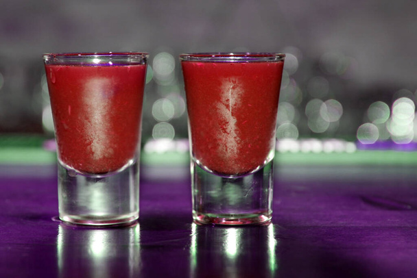 Lähikuva kaksi punaista cocktail laukausta baaritiskillä hämärtyneellä taustalla - Valokuva, kuva