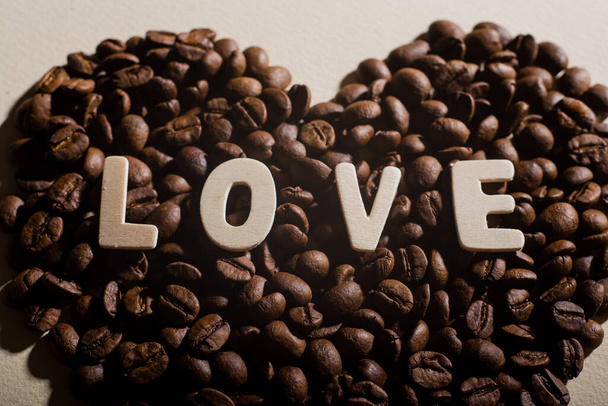 Close-up of coffee beans in the shape of a heart and the inscription love - Foto, imagen