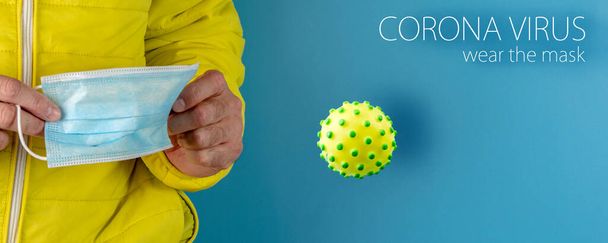 человек в желтой куртке использует защитную маску от вируса короны на синем фоне, высокой боевой готовности и борьбы с болезнью, COVID-19 SARS, SARS-CoV, вирус 2020 - Фото, изображение