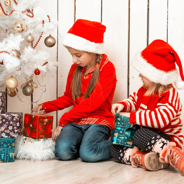 two little girls open christmas presents sitting on the floor - Fotoğraf, Görsel