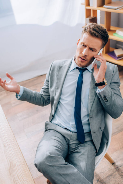High angle view of businessman in suit talking on smartphone in office  - Photo, image