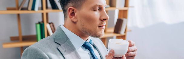 Businessman with closed eyes holding cup of coffee in office, banner  - Foto, Imagem