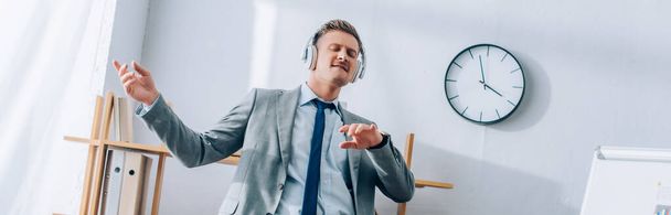 Empresario en auriculares bailando mientras trabaja en la oficina, pancarta  - Foto, imagen