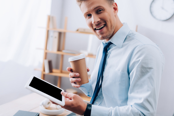 Homme d'affaires joyeux avec du café à emporter et tablette numérique regardant l'appareil photo  - Photo, image