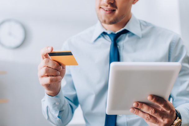 Cropped view of digital tablet and credit card in hands of smiling businessman  - Photo, Image