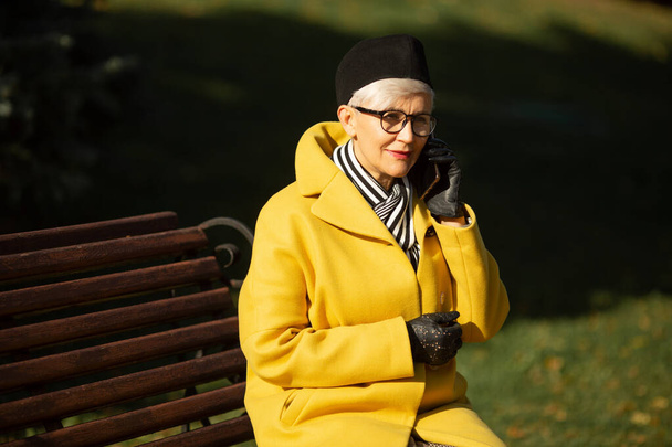 adult woman in glasses in the park in autumn with a mobile phone - Foto, Bild