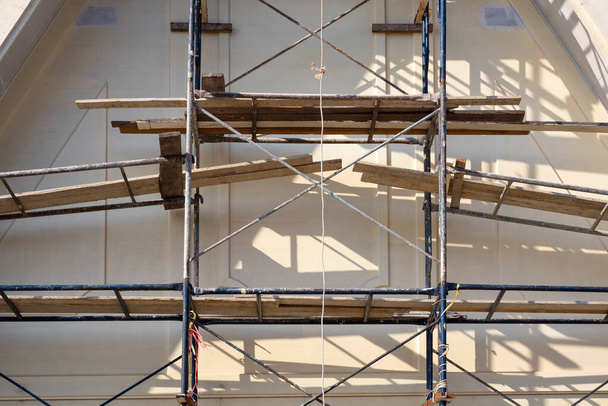 Sunlight and shadow on surface of metal scaffolding in front of roof truss structure under construction, renovation and improvement concept - Photo, Image