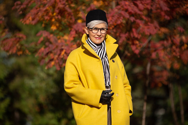 mujer adulta con abrigo amarillo en el parque en otoño - Foto, imagen