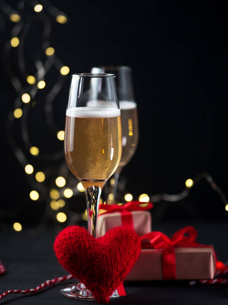 Copas de champán sobre una mesa de hormigón oscuro y un corazón rojo con regalos. Celebra el Día de San Valentín - Foto, Imagen