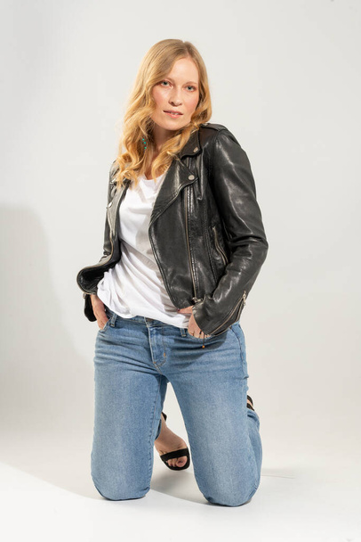 Blonde young woman dressed in denim clothes and zip-up leather jacket - Foto, Imagem