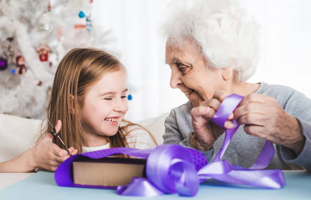 Grandmother with granddaughter decorating gifts - 写真・画像