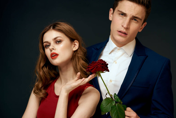 νεαρό ζευγάρι αγκαλιές γοητεία κόκκινο τριαντάφυλλο σχέση μαύρο φόντο - Φωτογραφία, εικόνα