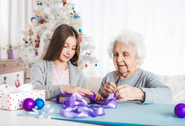 Grandmother with granddaughter decorating gifts - Photo, Image