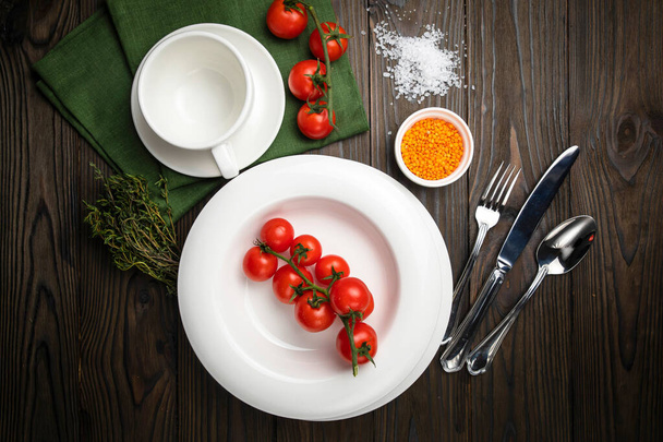 The dishes are laid out on a wooden table. Cherry, grass, utensils, sea salt - Foto, Imagen
