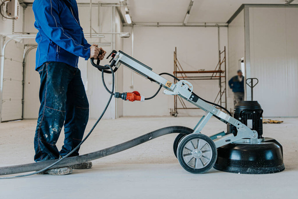 Construction worker using machine polishing surface floor smoothing and finishing hardener or epoxy concrete in the factory. - Fotoğraf, Görsel