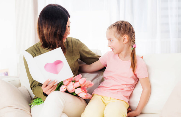 Mother and daughter smiling on the couch with gifts - Photo, Image