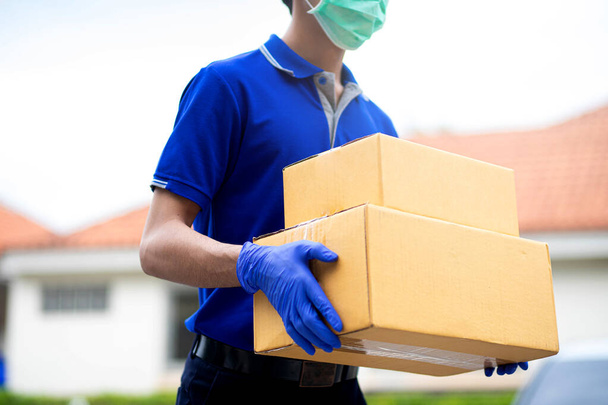 Чоловік-доставка одягнений в рукавички і маски, щоб тримати картонні коробки
 - Фото, зображення