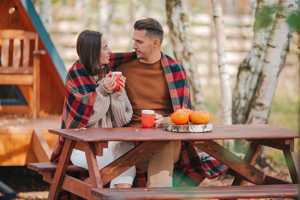 Молода пара з кавою на подвір'ї свого будинку восени
 - Фото, зображення