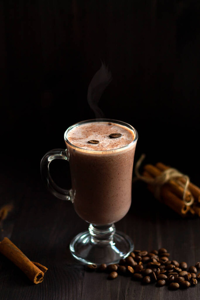 hot drinks. cup of hot chocolate. glass of hot cocoa with whipped cream, coffee beans and cinnamon sticks on a dark background. hot drinks on a wooden background. winter and autumn.vertical.copy space - Zdjęcie, obraz