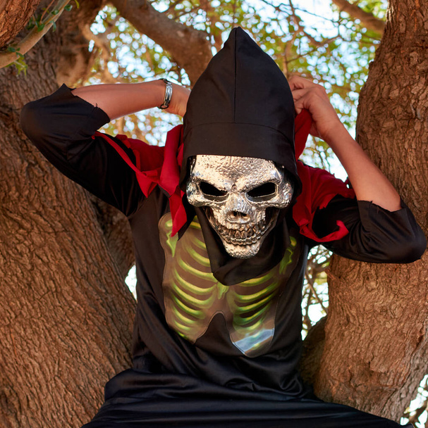 Porträtaufnahme einer Person im Halloween-Kostüm, während sie auf einem Baum sitzt - Foto, Bild