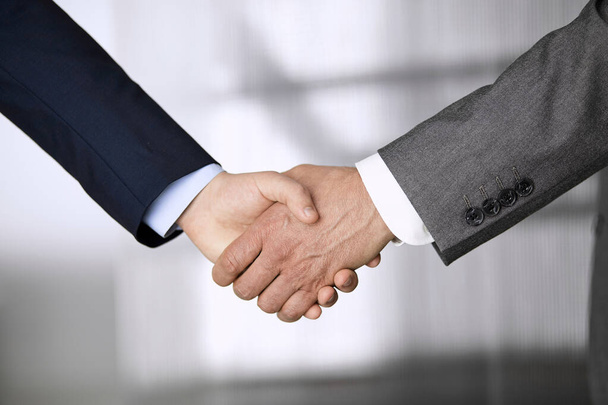 Business people in office suits standing and shaking hands, close-up. Business communication concept. Handshake and marketing - Photo, image