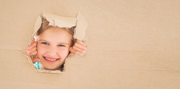 Little girl gazing from hole in cardboard - Foto, imagen