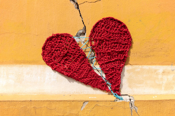 Zagreb / Croácia-06 de abril de 2020: Stitched vermelho, wowen coração em torno de fratura na parede - Foto, Imagem