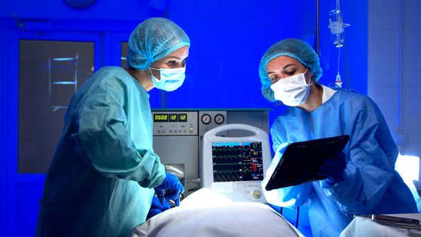Medici di sesso femminile che eseguono interventi chirurgici in sala operatoria - Foto, immagini