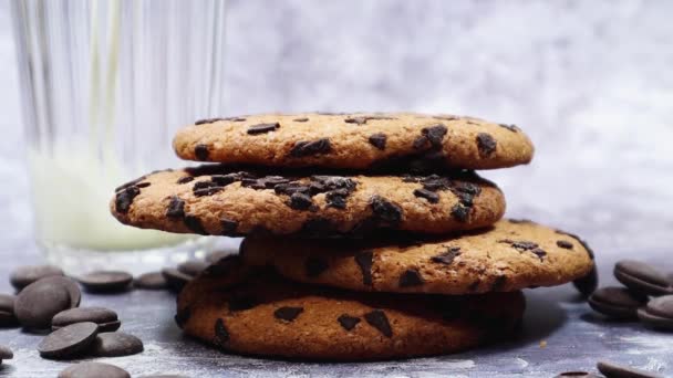 アメリカのチョコレートチップクッキー、牛乳は灰色の背景の背景にガラスに注ぎ込まれます。チョコレートチップと伝統的なラウンドクリスピー生地.パン屋さん。おいしいデザート,ペストリー - 映像、動画
