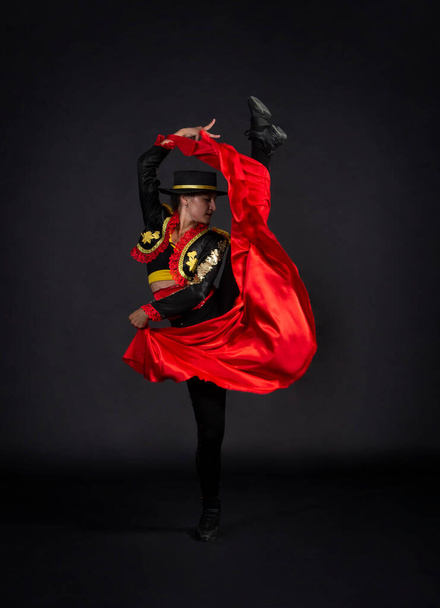 Plastic girl gracefully dancing in a stage costume stylized as a bullfighter. Studio shooting on a dark background. - Valokuva, kuva
