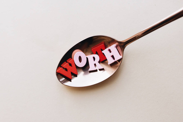 colorful wooden letters in spoon, WORTH lettering  - 写真・画像