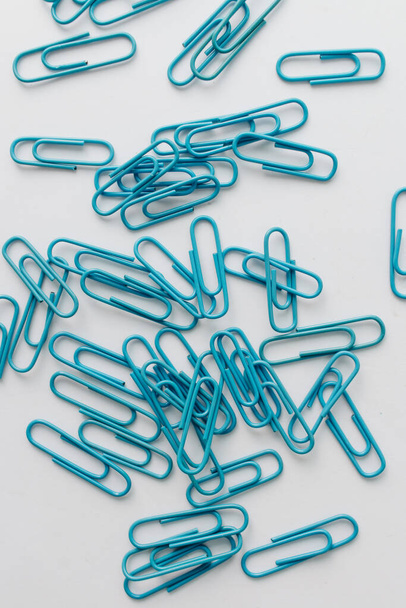 Vista superior de clips de papel azul dispersos, papelería organizada aislada en blanco - Foto, Imagen