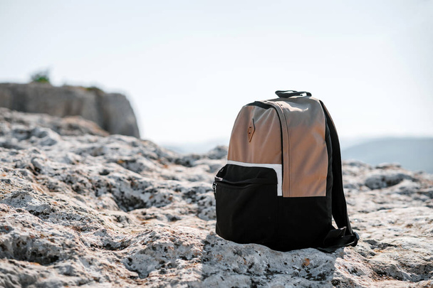 The backpack stands on a high rock, below you can see the landscape, the concept of hiking and tourism - 写真・画像