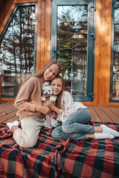 Onnelliset lapset istuvat talonsa terassilla syksyllä - Valokuva, kuva