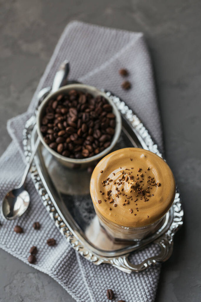 Glass of Iced Dalgona Coffee, trendy fluffy creamy whipped coffee and milk on grey background. - Foto, imagen