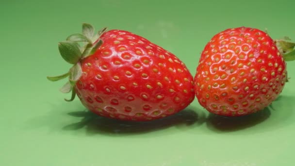 Fresas sobre un fondo verde primer plano. Frutas orgánicas maduras. Vídeo 4K. - Imágenes, Vídeo