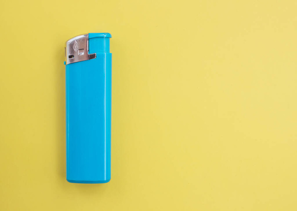 A turquoise lighter on a bright colored background with copy space. Smoking concept. - Photo, Image