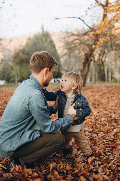 Ευτυχισμένος πατέρας και γιος διασκεδάζουν στο πάρκο του φθινοπώρου - Φωτογραφία, εικόνα