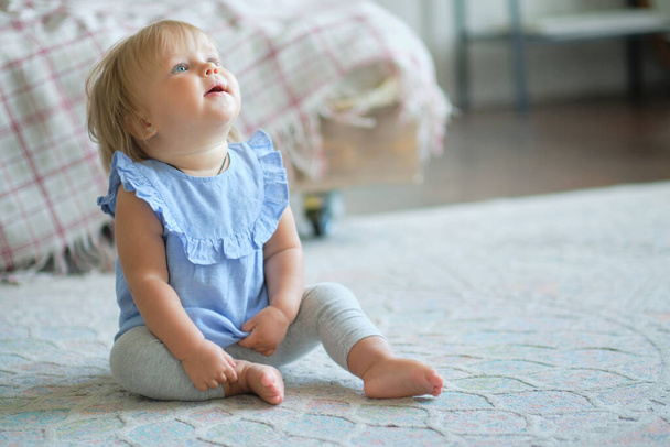 gyermekkor, gyermekkor és emberek koncepciója. boldog kislány ül a szőnyegen otthon. - Fotó, kép