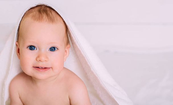 フードがカメラを覗き込むと、青い目をした可愛い赤ちゃんがタオルに包まれています。風呂の後のきれいな赤ん坊は、子供の世話をする。スペースのコピー. - 写真・画像