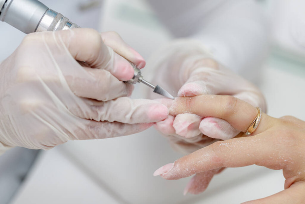 Procedura di manicure con dispositivo nel salone di bellezza. Primo piano del processo - Foto, immagini