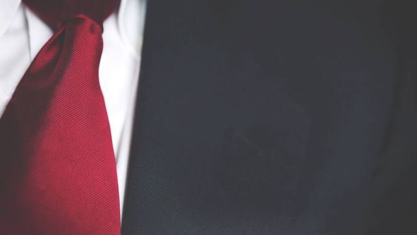 una chaqueta de traje de negocios negro con camisa blanca y corbata roja, pecho de hombre primer plano textura fondo con espacio de copia. - Foto, imagen