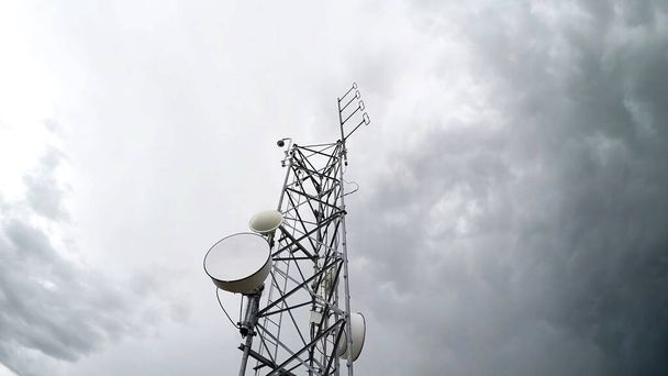 Radio antenna tower telecommunication against cloudy white sky in low angle view. Isolated background. - Photo, Image