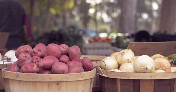 Czerwone ziemniaki i biała cebula na drewnianym wiadrze na rynku. Świeże warzywa na wolnym powietrzu tle rynku. - Zdjęcie, obraz