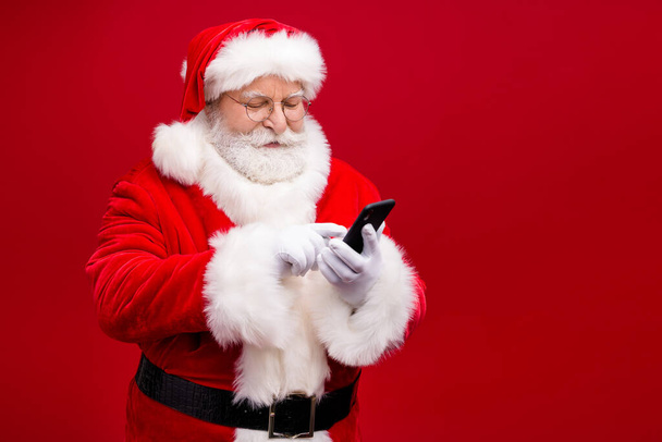 Portrait of his he nice attractive handsome focused Santa grandfather using gadget 5g service blog blogger post comment feedback isolated over bright vivid shine vibrant red color background - Fotografie, Obrázek