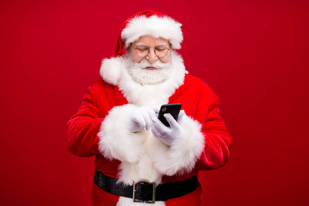 Portrait of his he nice attractive handsome cheerful focused Santa father using device gadget 5g web service blog post smm comment isolated over bright vivid shine vibrant red color background - Foto, Imagem