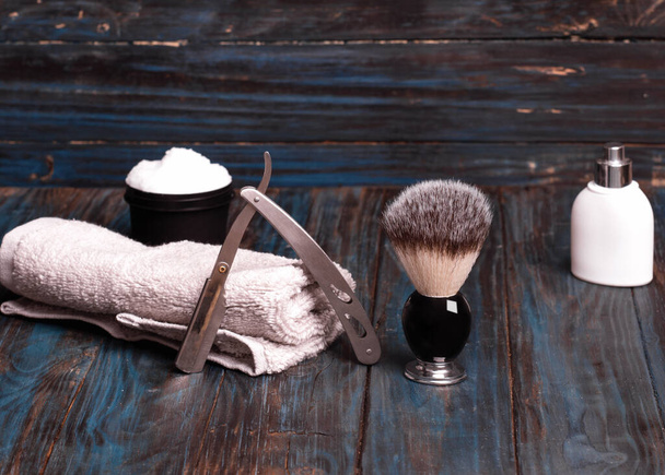 Razors, brush, balsam, towels and foam on a wood background - Foto, afbeelding