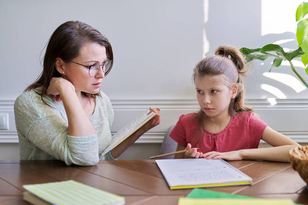 Mother and daughter child study together at home, sitting at table - Photo, Image