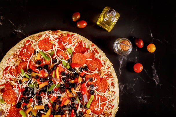 Extra large pizza with olives, pepperoni and tomatoes on black background. - Photo, Image